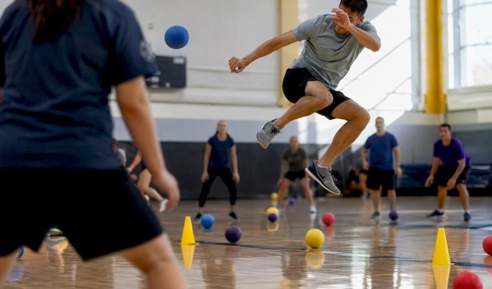Corporate dodgeball player dodging ball in gym