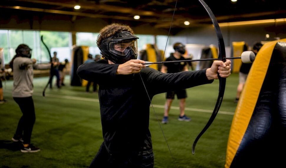 Teens playing combat archery in arena