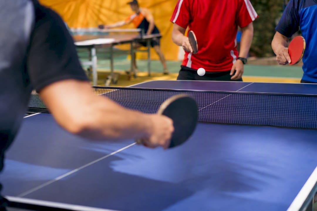 Two doubles teams playing ping pong in a tournament