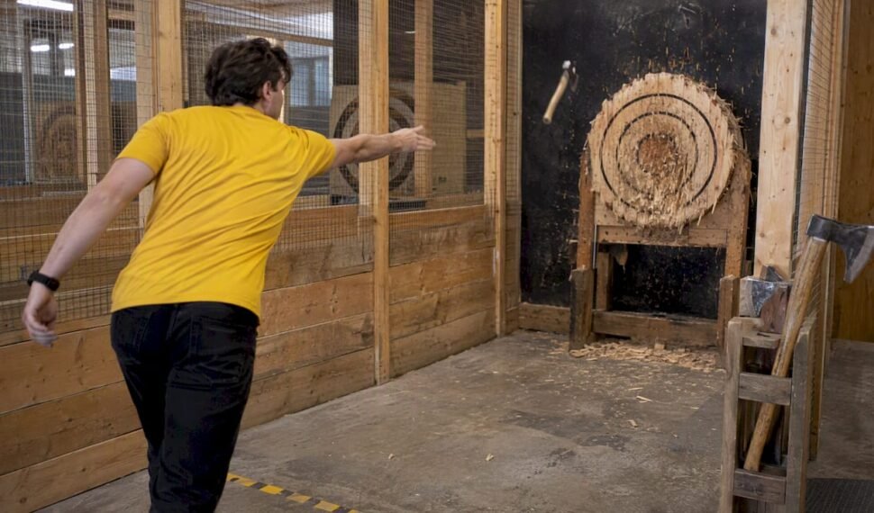 Participant throwing hatchet in indoor axe lane