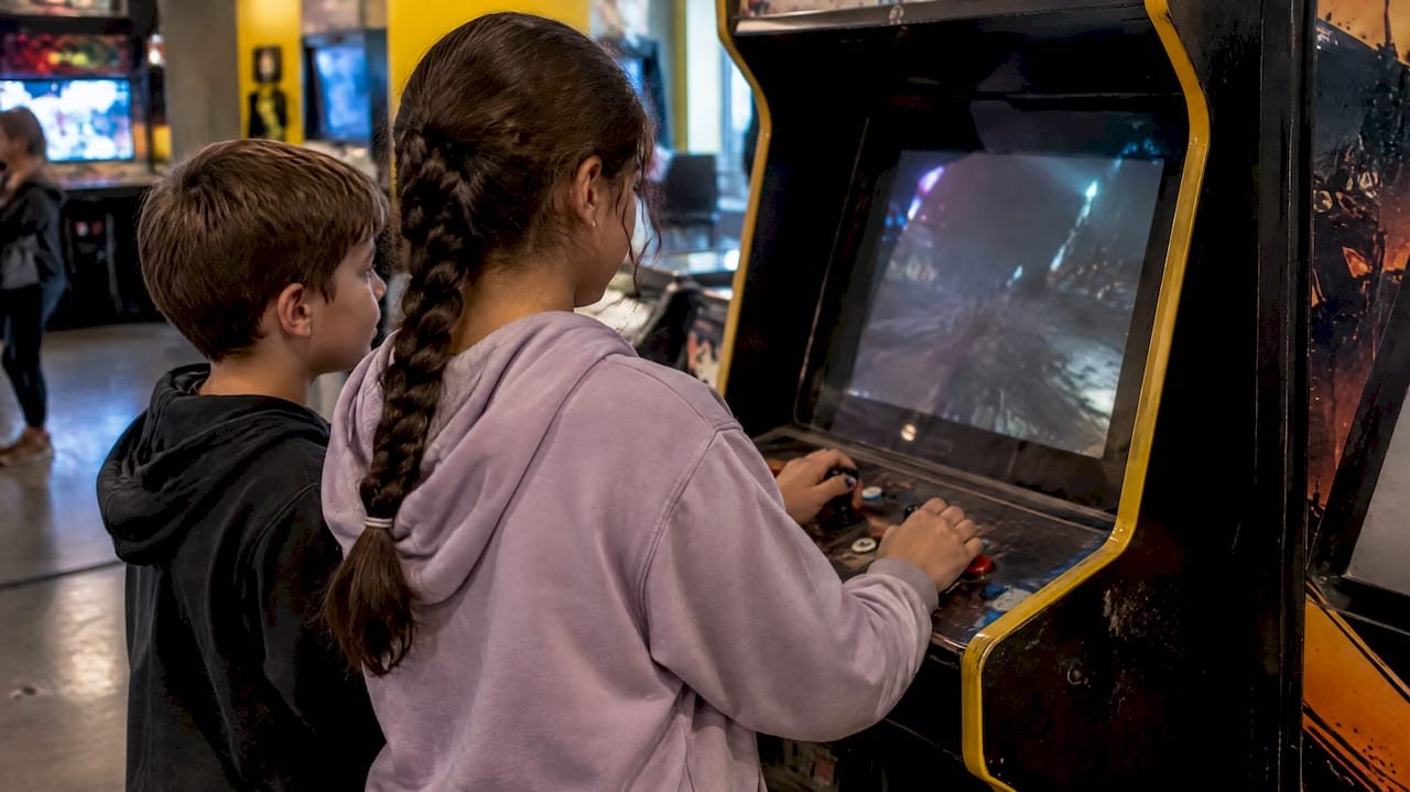 Siblings playing an arcade game indoors