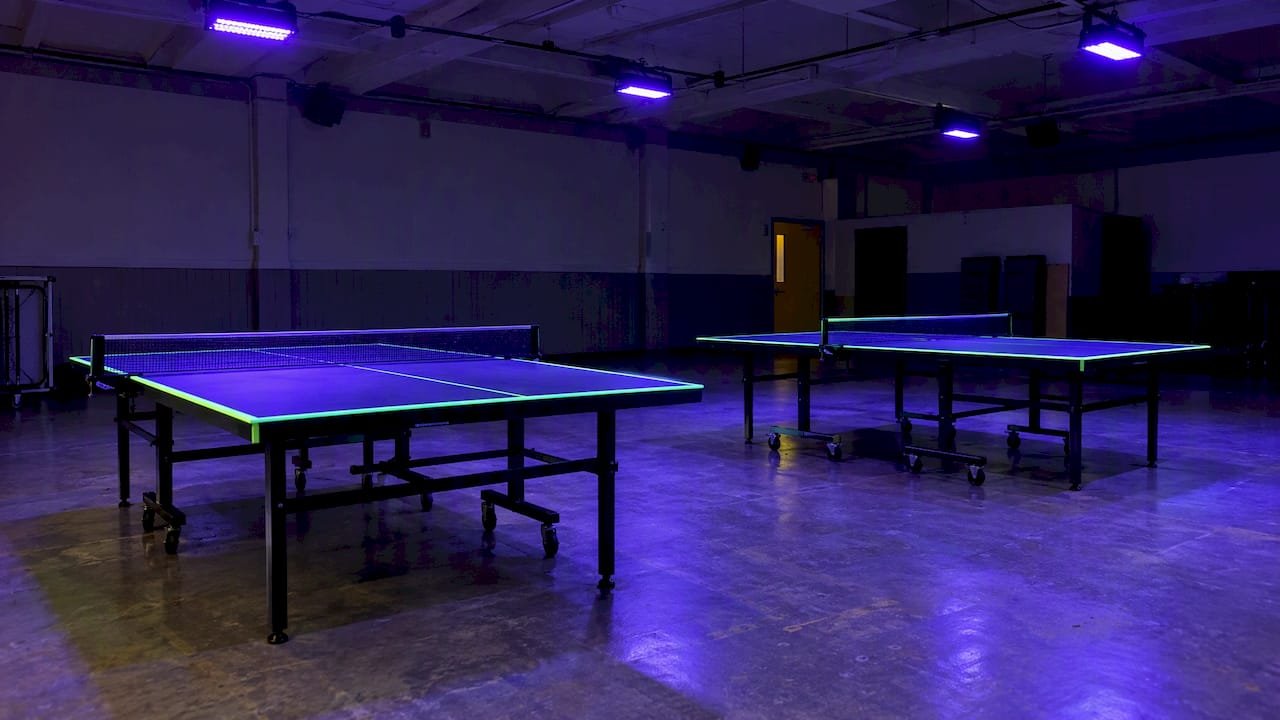 Blacklights mounted high over evenly lit tables
