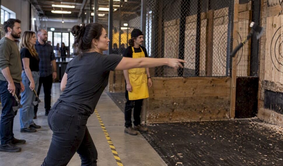 Coworkers taking turns at an axe throwing lane